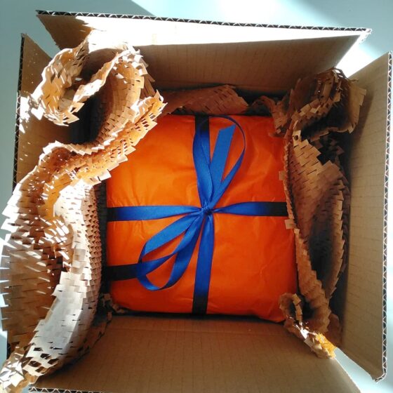 Paczka zapakowana w pomarańczową bibułę, gotowa do wysyłki