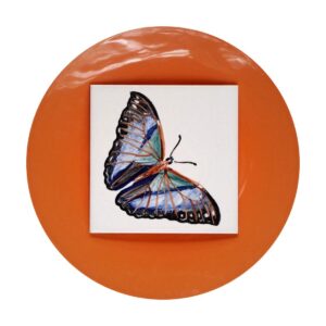 Niebiesko-fioletowy motyl namalowany ręcznie na kafelku ceramicznym