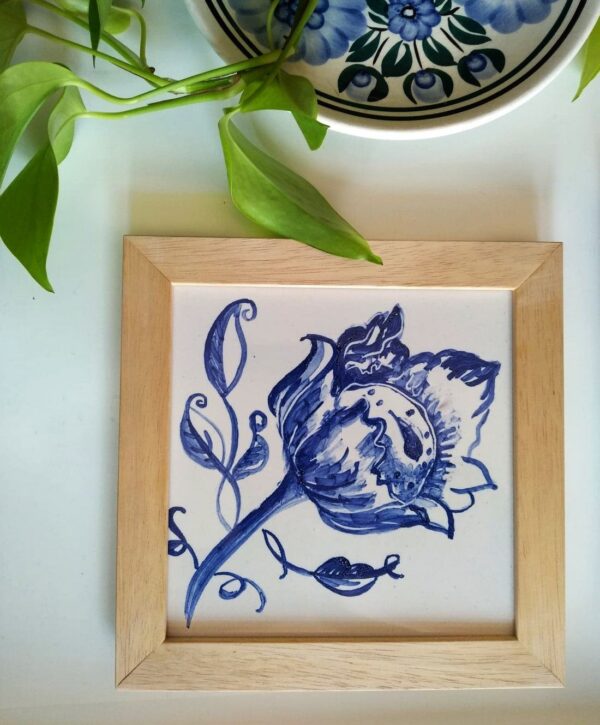 Kafelek z niebieskim kwiatem w ramce drewnianej