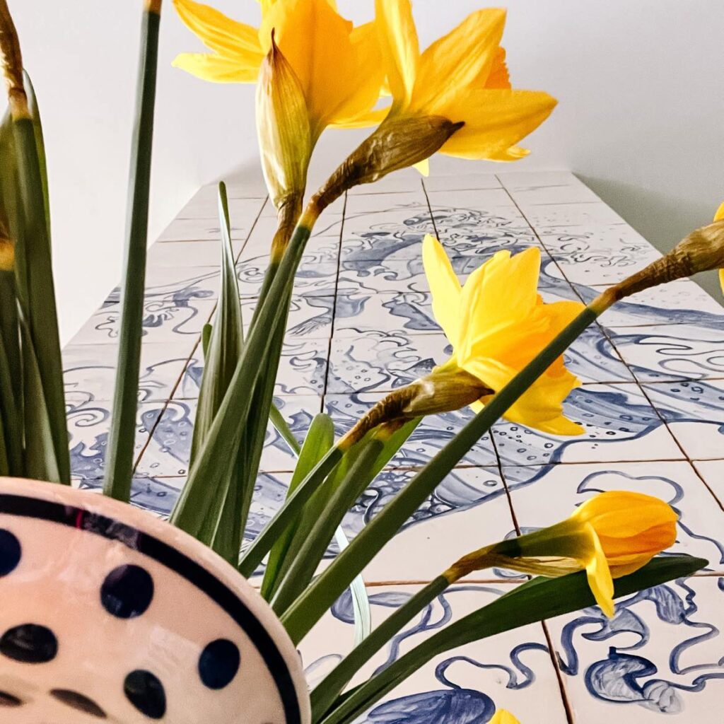 bukiet żonkili na tle ściany z obrazem ceramicznym