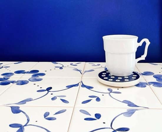 porcelanowy biały kubek i ciemnoniebieska ściana, a kafelki jako blat