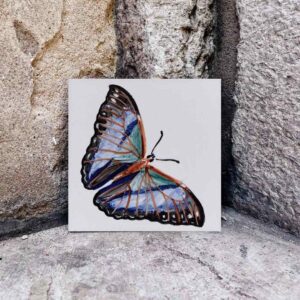 Niebiesko-fioletowy motyl namalowany ręcznie na kafelku ceramicznym
