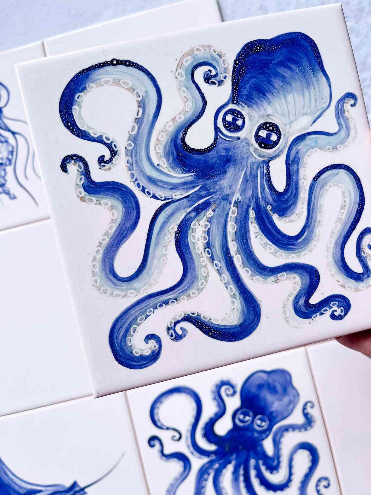 Ośmiornica o wielkich oczach i wielu mackach namalowana w kolorze na kafelku ceramicznym