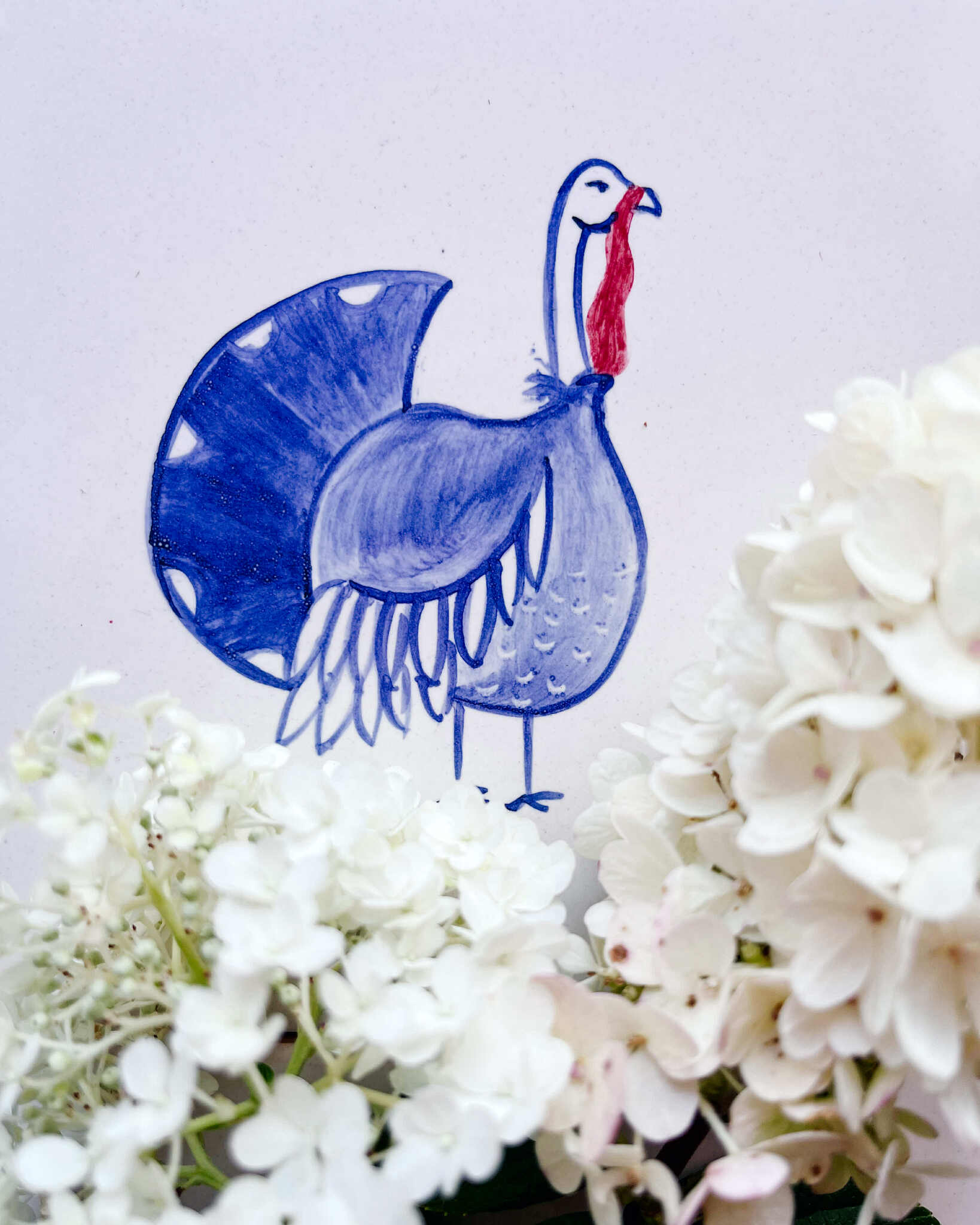 płytka z Indorem indykiem namalowana, leżąca w hortensjach