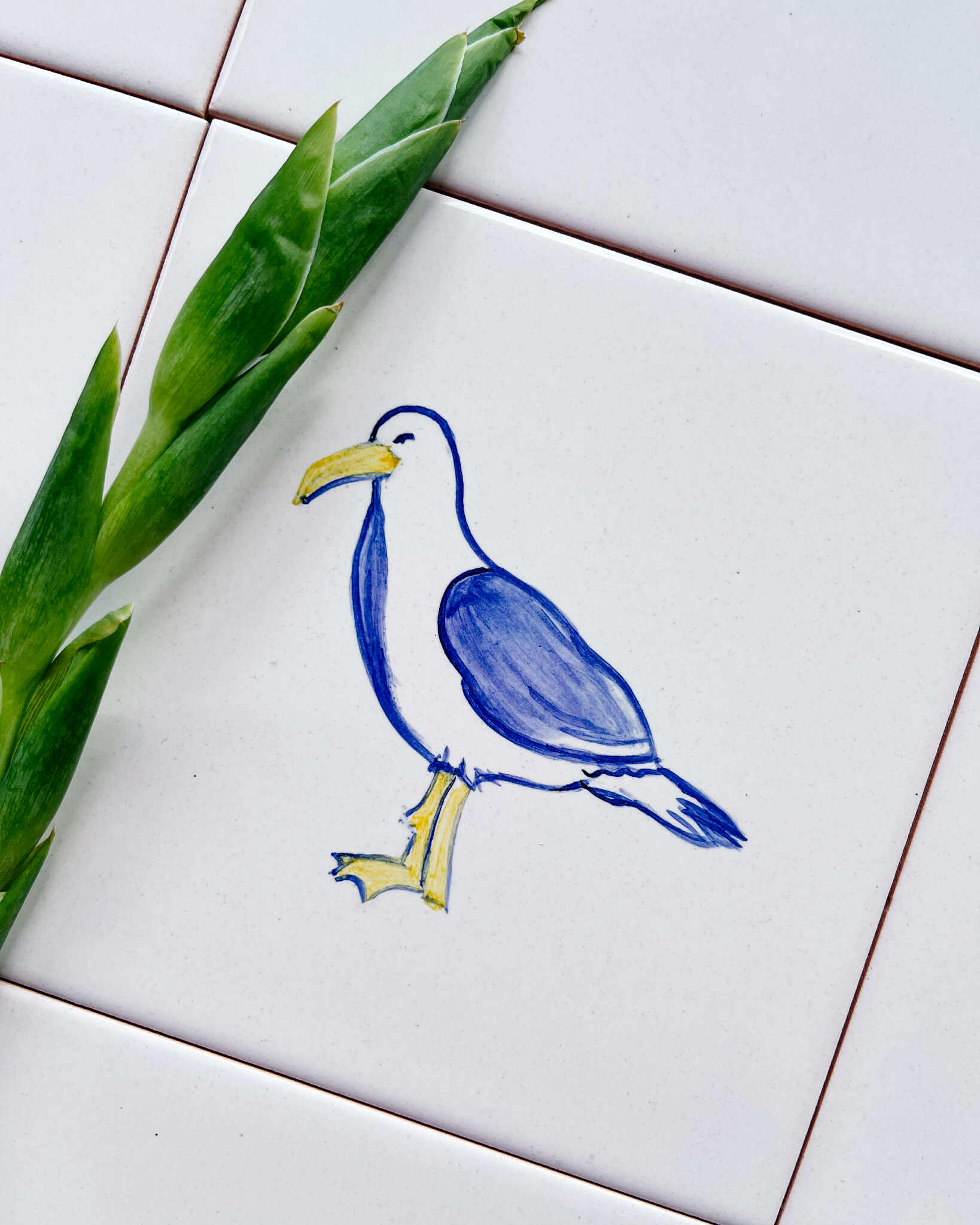 Płytka z ręcznie namalowaną mewą, kolorowa i idealnie do niej pasujące białe płytki