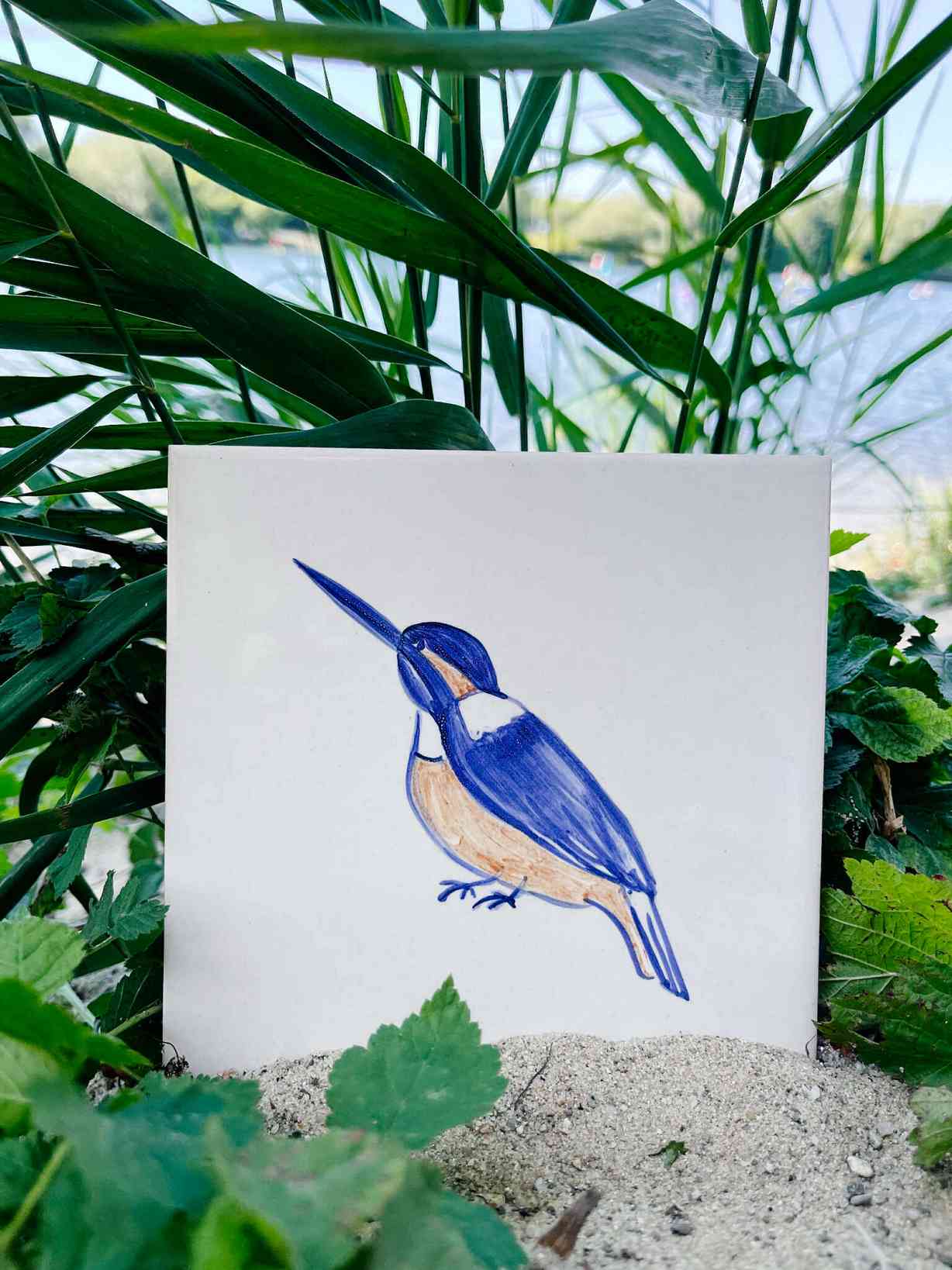 Zimorodek na kafelku ceramicznym namalowany ukryty wśród traw