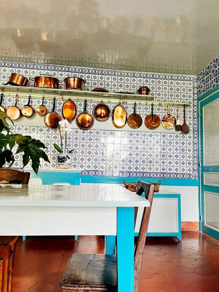 Kuchnia Cloude'a Moneta w Giverny - stoł, ciepłobrązowa posadzka, biało-niebieskie kafelki i miedziane garnki 