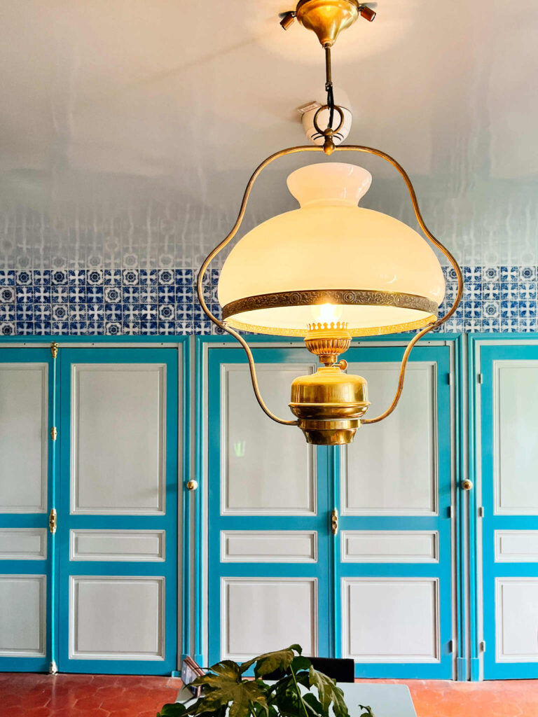 Lampa nad stołem kuchennym w domu Moneta w Giverny, na ścianie szafa, a nad nią - kafelki ręcznie malowane z Rouen