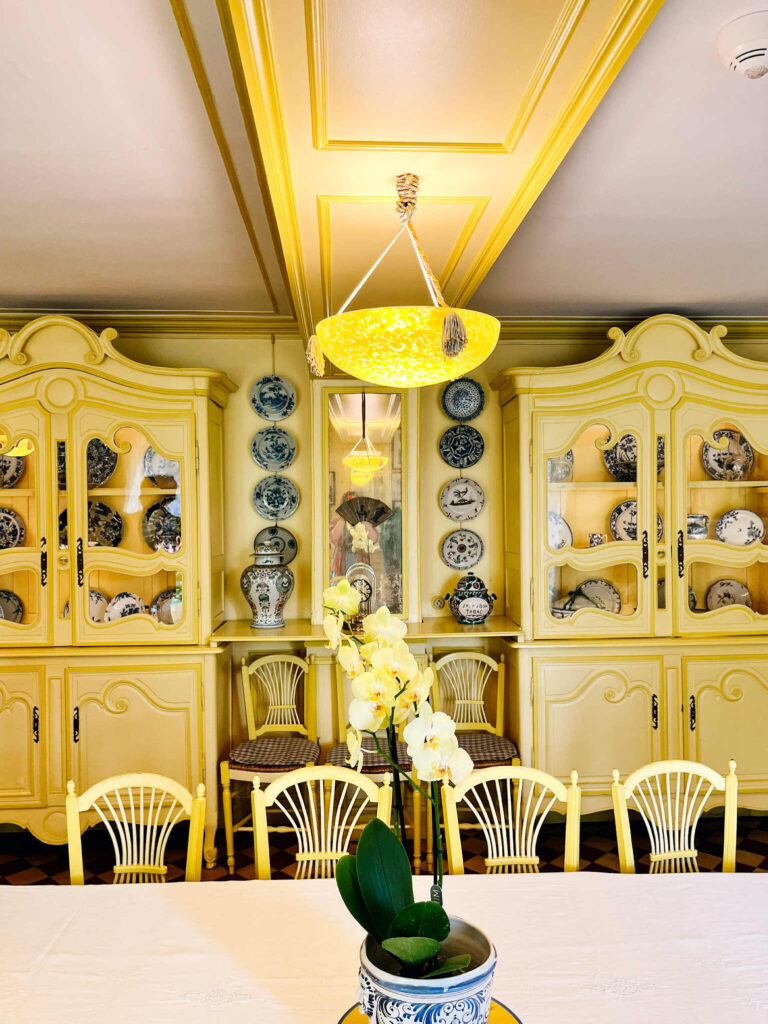 Żółte kredensy, ściany, krzesła i lampa - widok na jadalnię w domu Moneta w Giverny