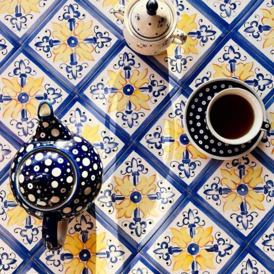 Żółto-niebieski nasycony ornament namalowany ręcznie na kafelkach ceramicznych, na płytkach kubek herbaty, dzbanek na herbatę i cukiernica