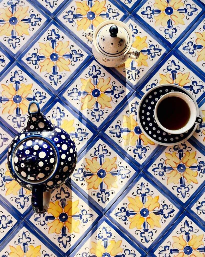 Żółto-niebieski nasycony ornament namalowany ręcznie na kafelkach ceramicznych, na płytkach kubek herbaty, dzbanek na herbatę i cukiernica