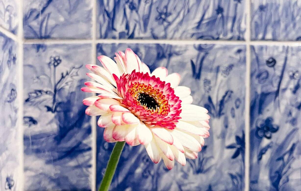 Kafelki ręcznie malowane to ciekawa propozycja do łazienki - tutaj nad wanna wzór układający się w łąkę, w kolorze niebieskim