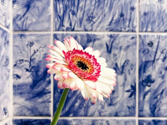 Kafelki ręcznie malowane to ciekawa propozycja do łazienki - tutaj nad wanna wzór układający się w łąkę, w kolorze niebieskim