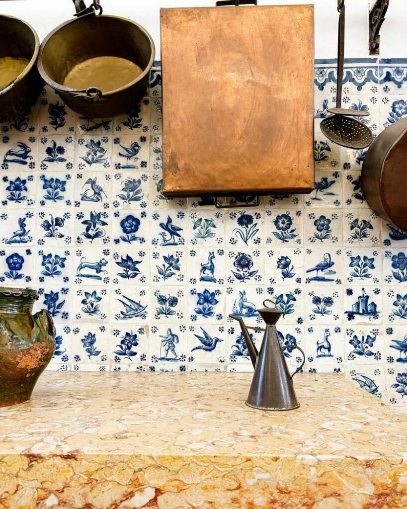 Kuchnia w Palacio Pimenta w Lizbonie ze ścianą w biało-niebieskie kafelki ręcznie malowane, kamienny blat i metalowe naczynia