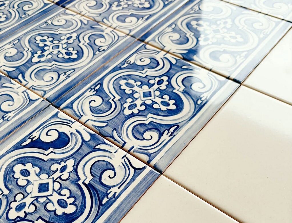 Płytki azulejos z biało-niebieskim wzorem, malowane ręcznie, ułożone po skosie i zestawione z białymi kafelkami gładkimi